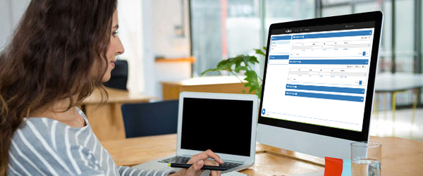 Woman sitting at computer with WebEDI interface on screen.